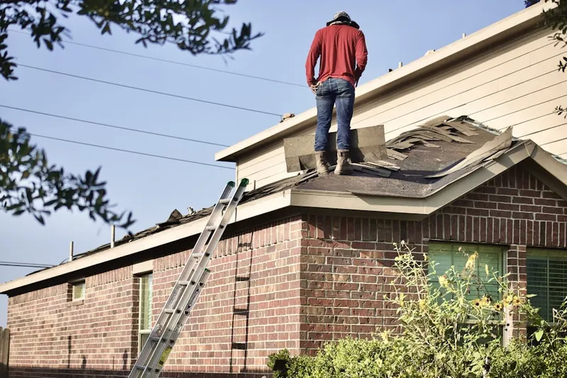Professional roofer working on a residential roof in Troy